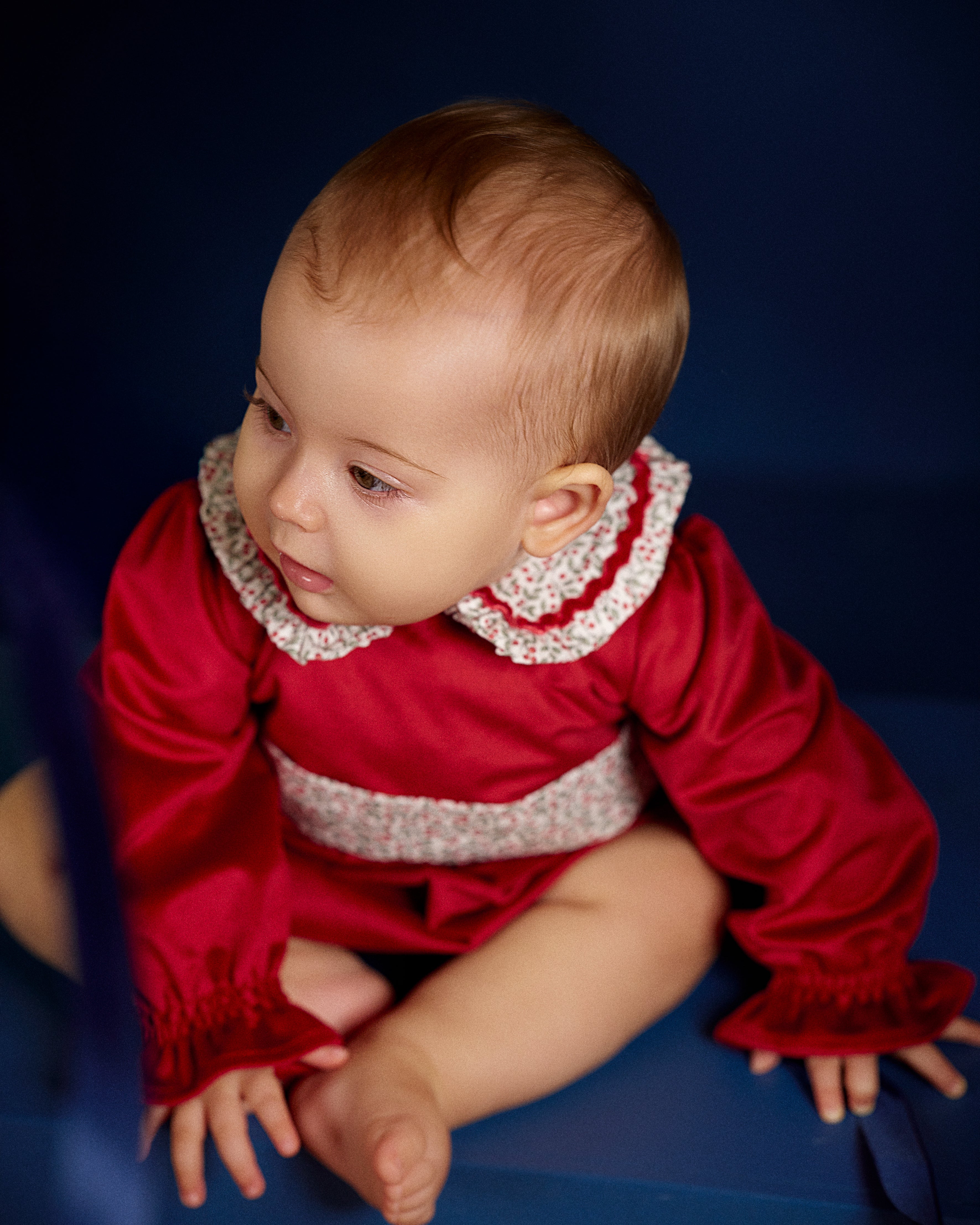 Baby girl wearing Deolinda Frosty red Christmas Day romper with floral collar