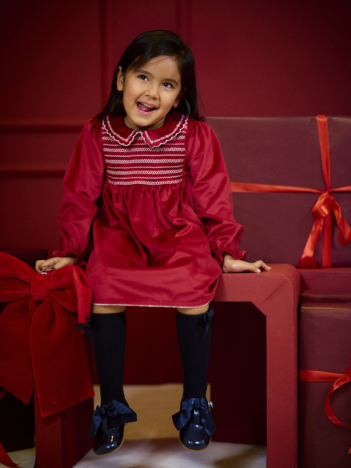 Girl wearing Deolinda Jolly red smocked Christmas party dress