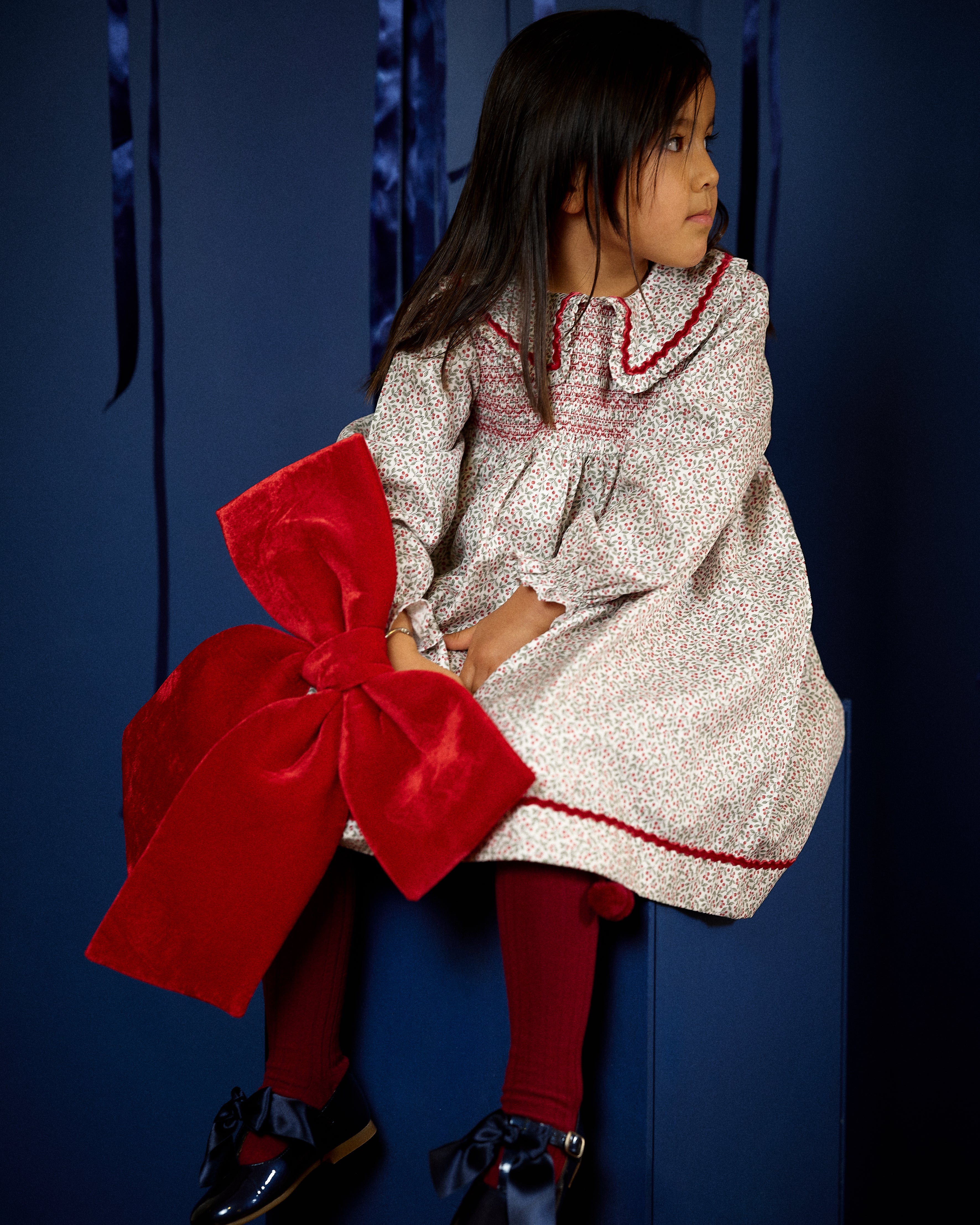 Girl wearing Deolinda Frosty floral smocked Christmas dress with red trim