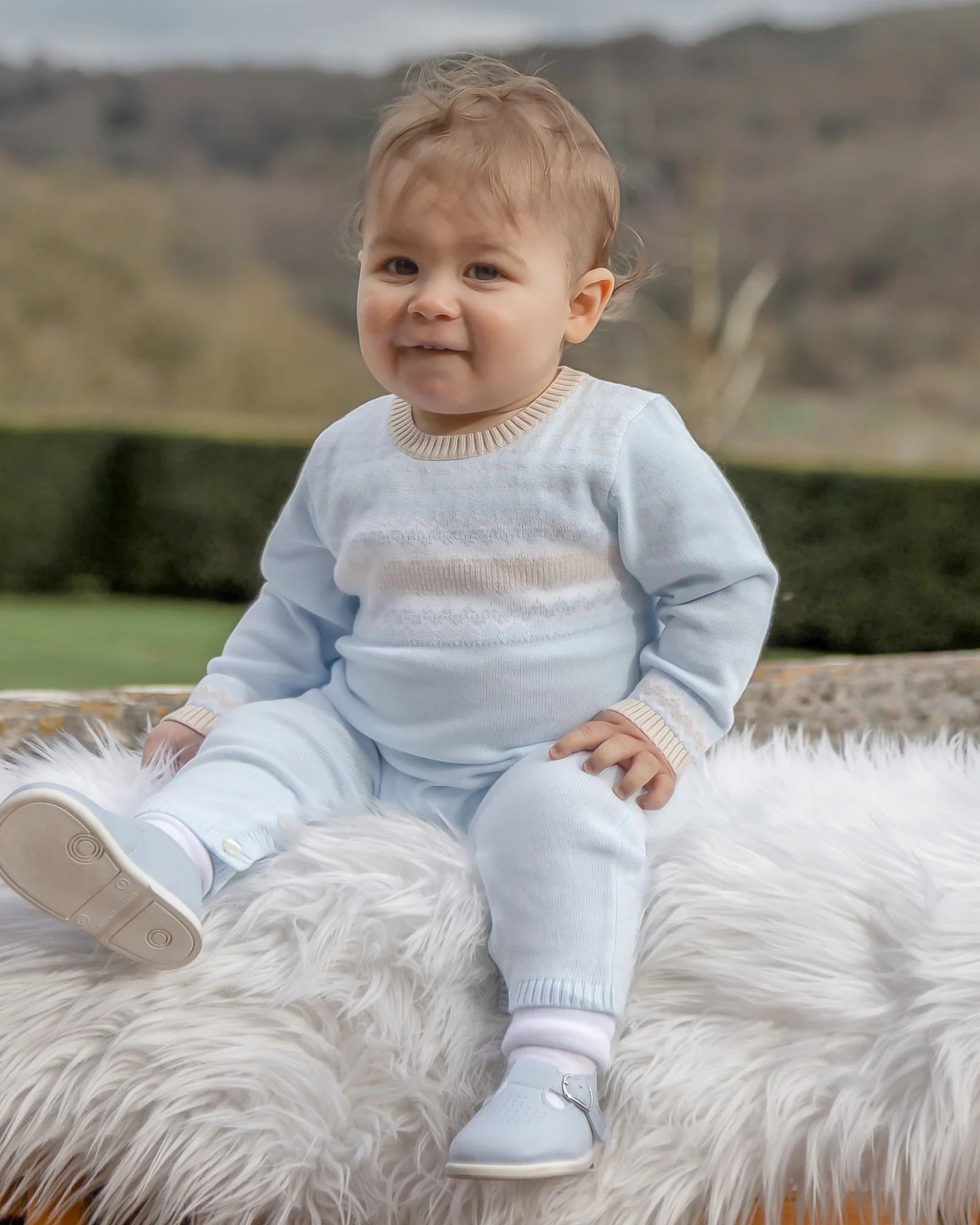 Baby boy wearing Emile et Rose Magnus pale blue knitted babygrow