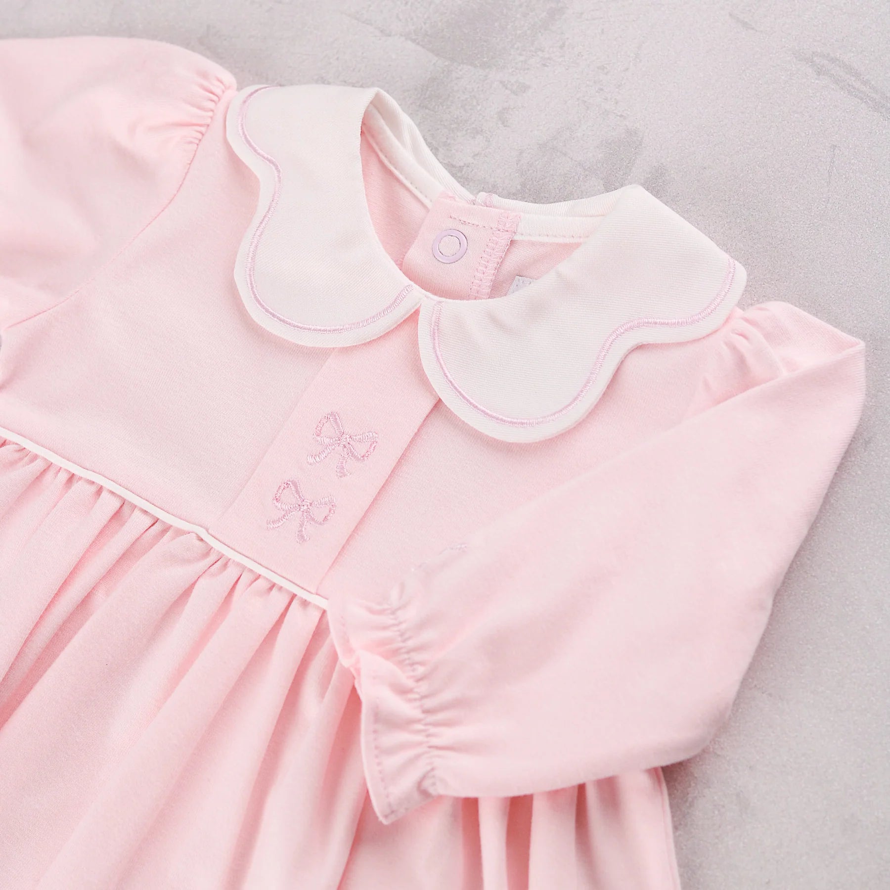 Close-up of the scalloped collar and bow embroidery on the Emile et Rose Maggie baby girls occasion dress