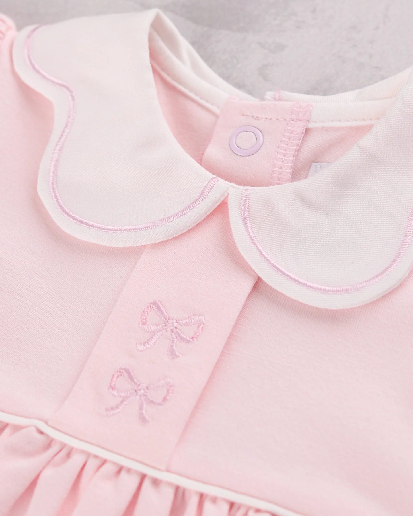 Close-up of a Emile et Rose Maggie baby dress in soft pink with a white Peter Pan collar