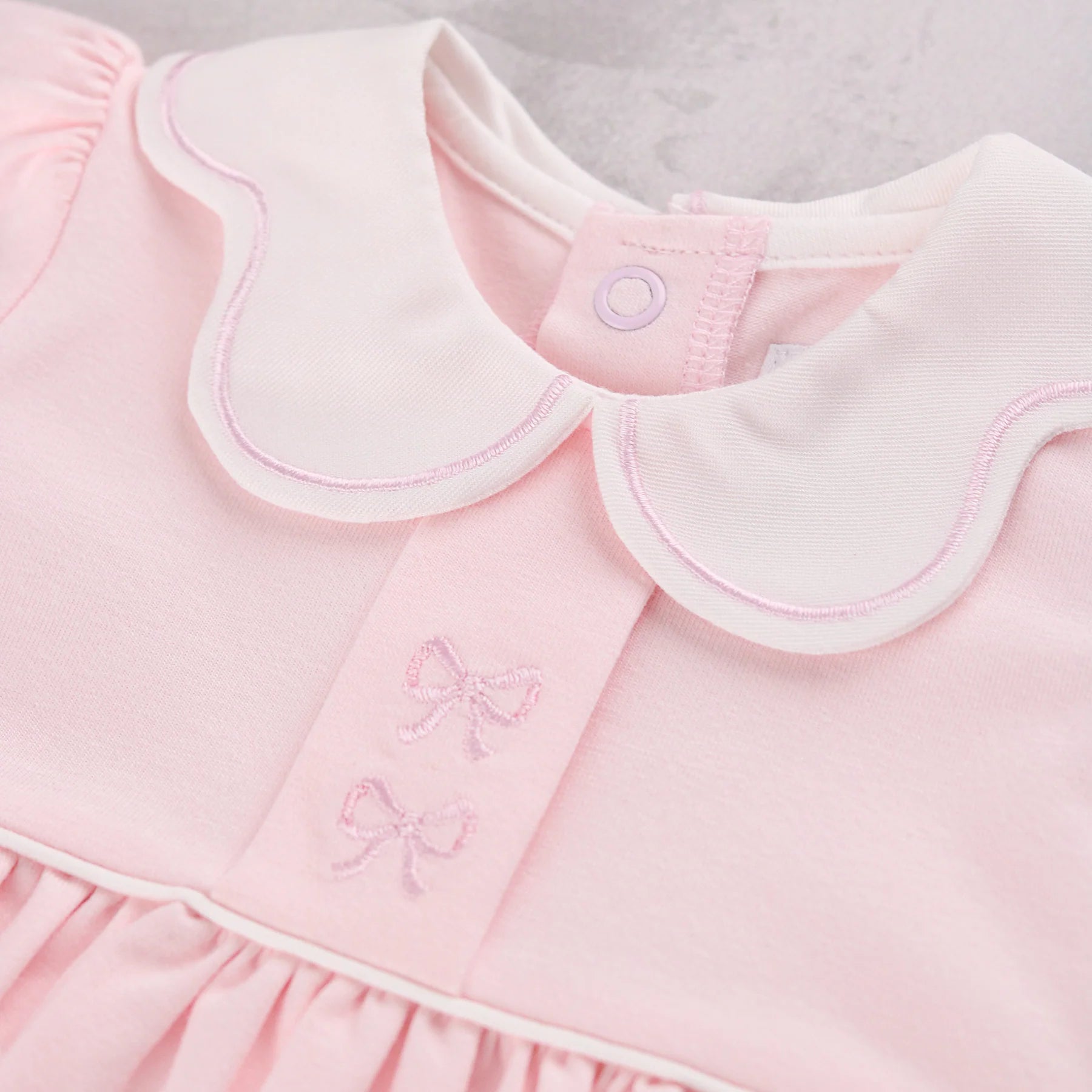 Close-up of a Emile et Rose Maggie baby dress in soft pink with a white Peter Pan collar