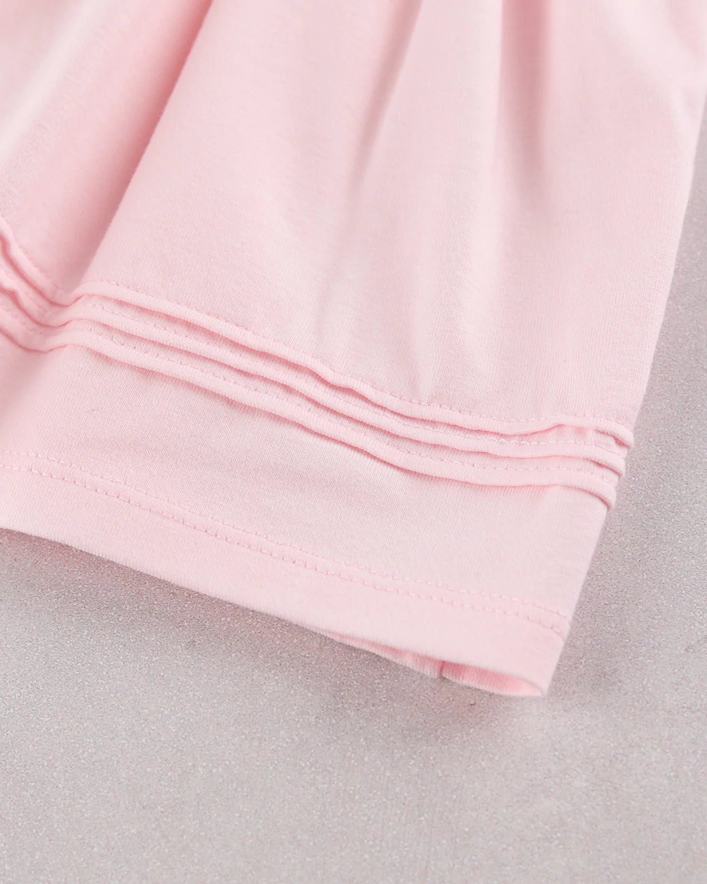 A close-up of a light pink baby girls occasion dress, showing the folded cuff on Emile et Rose dress