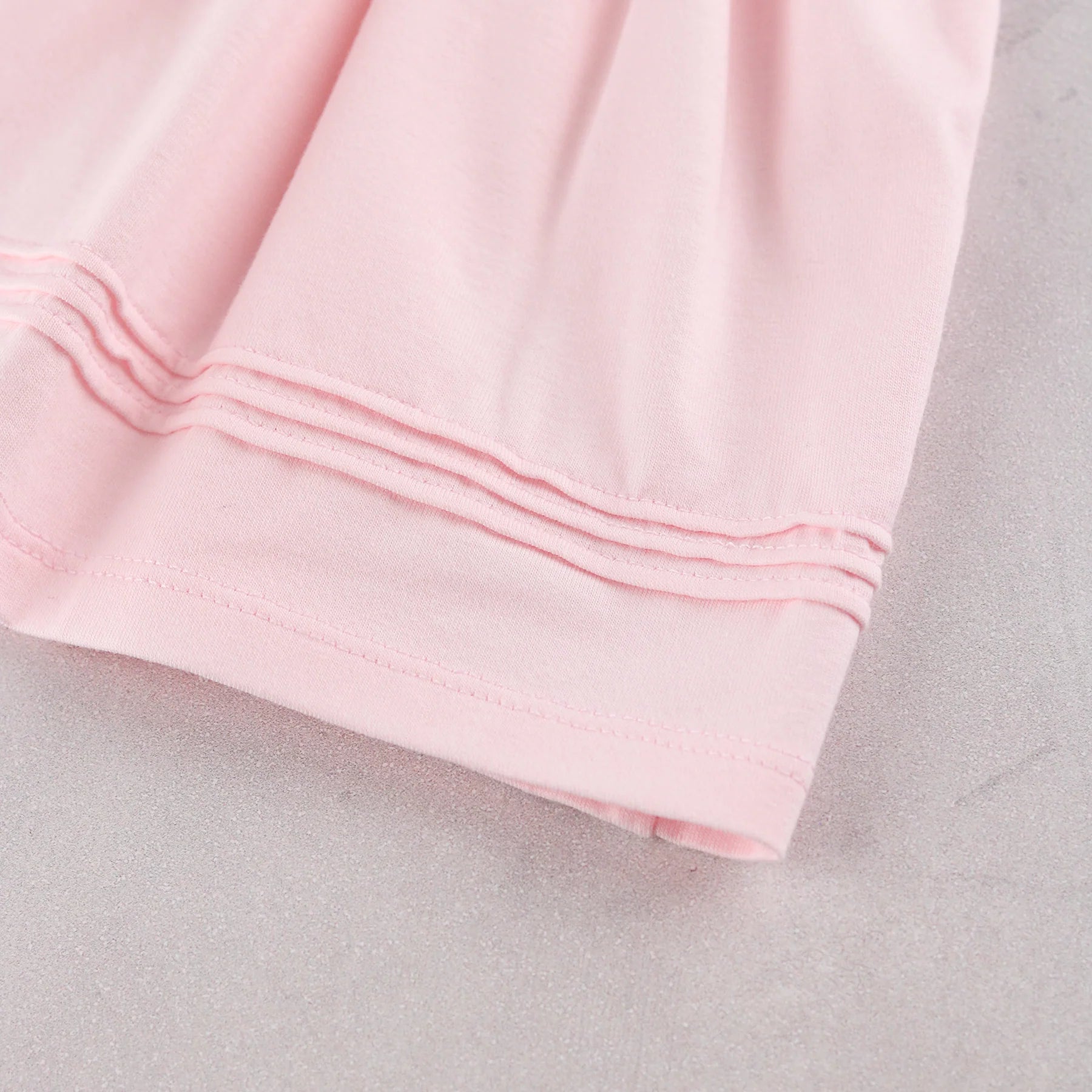 A close-up of a light pink baby girls occasion dress, showing the folded cuff on Emile et Rose dress