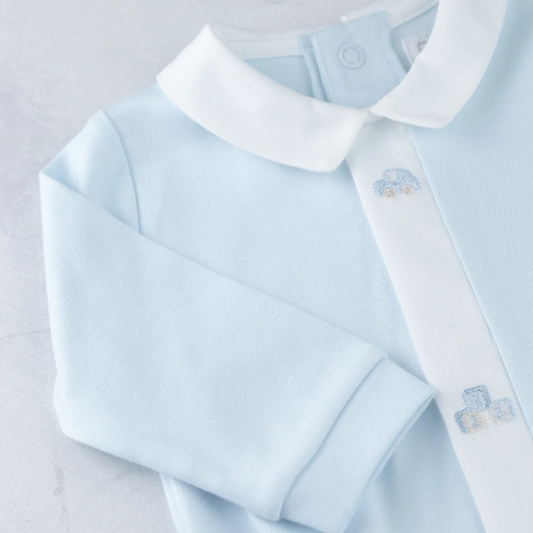 Close-up of Emile et Rose Kent babygrow mock front opening with embroidery detail.