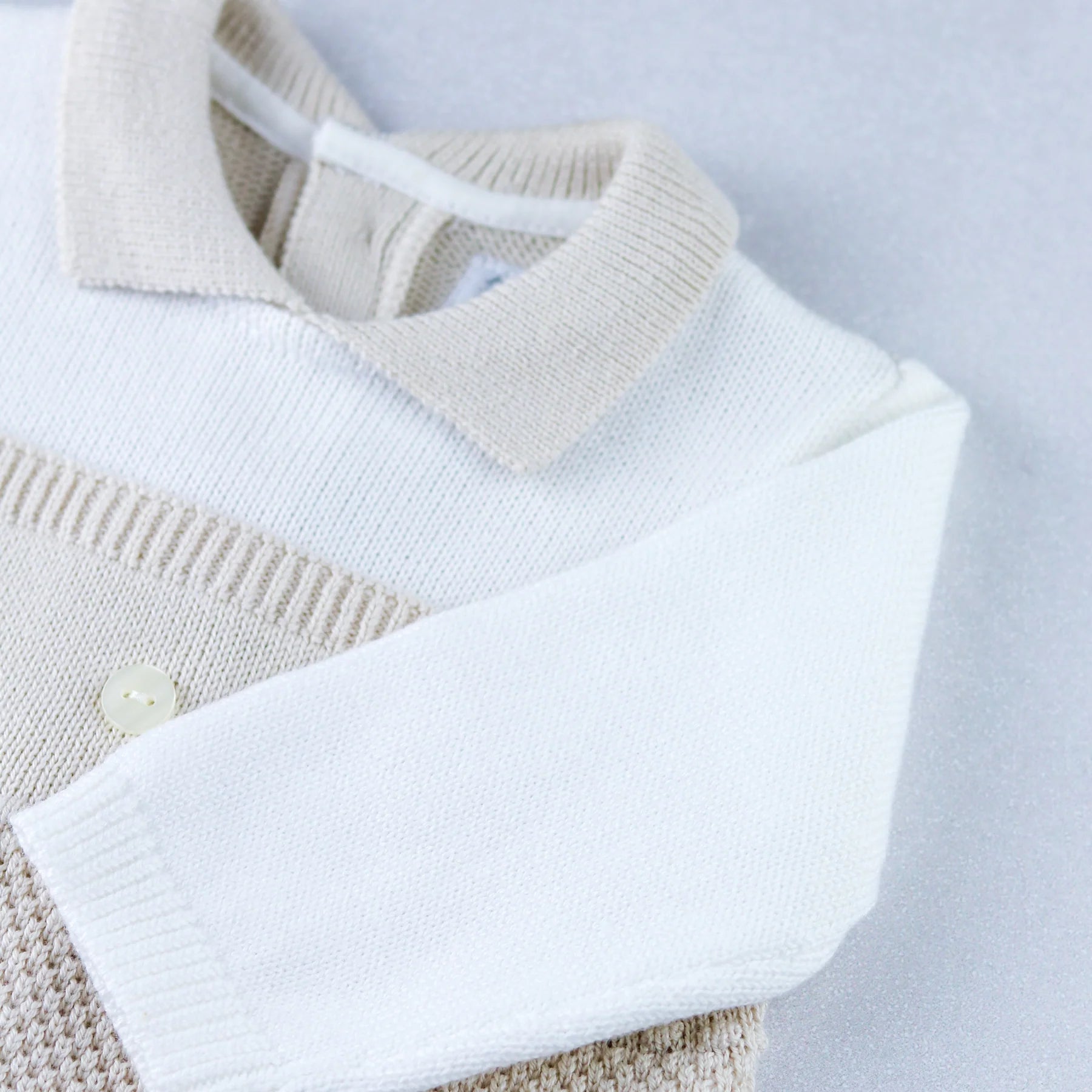 Flatlay of Emile et Rose Kenzie smart knitted babygrow with textured stone knit