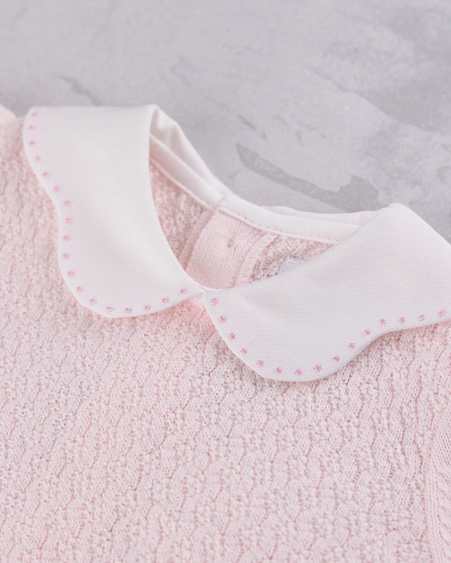 Close-up of the white scalloped collar with pink spot embroidery on the Emile et Rose Minny knit top