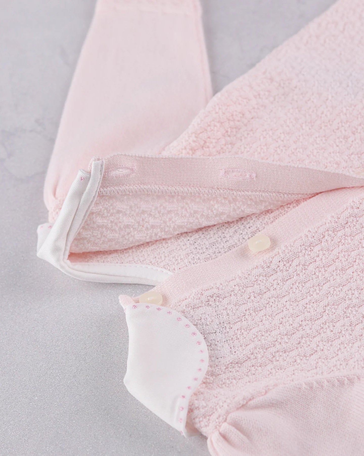 Close-up of the pearlised button fastening on the back of the Emile et Rose Minny knit top