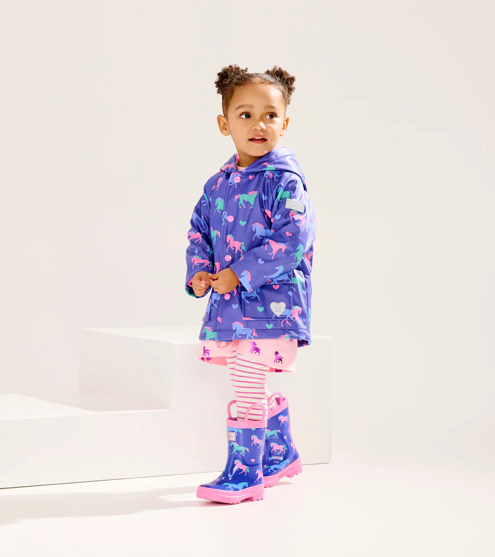 Toddler wearing Hatley Girls Hearts & Horses raincoat with matching boots – lifestyle