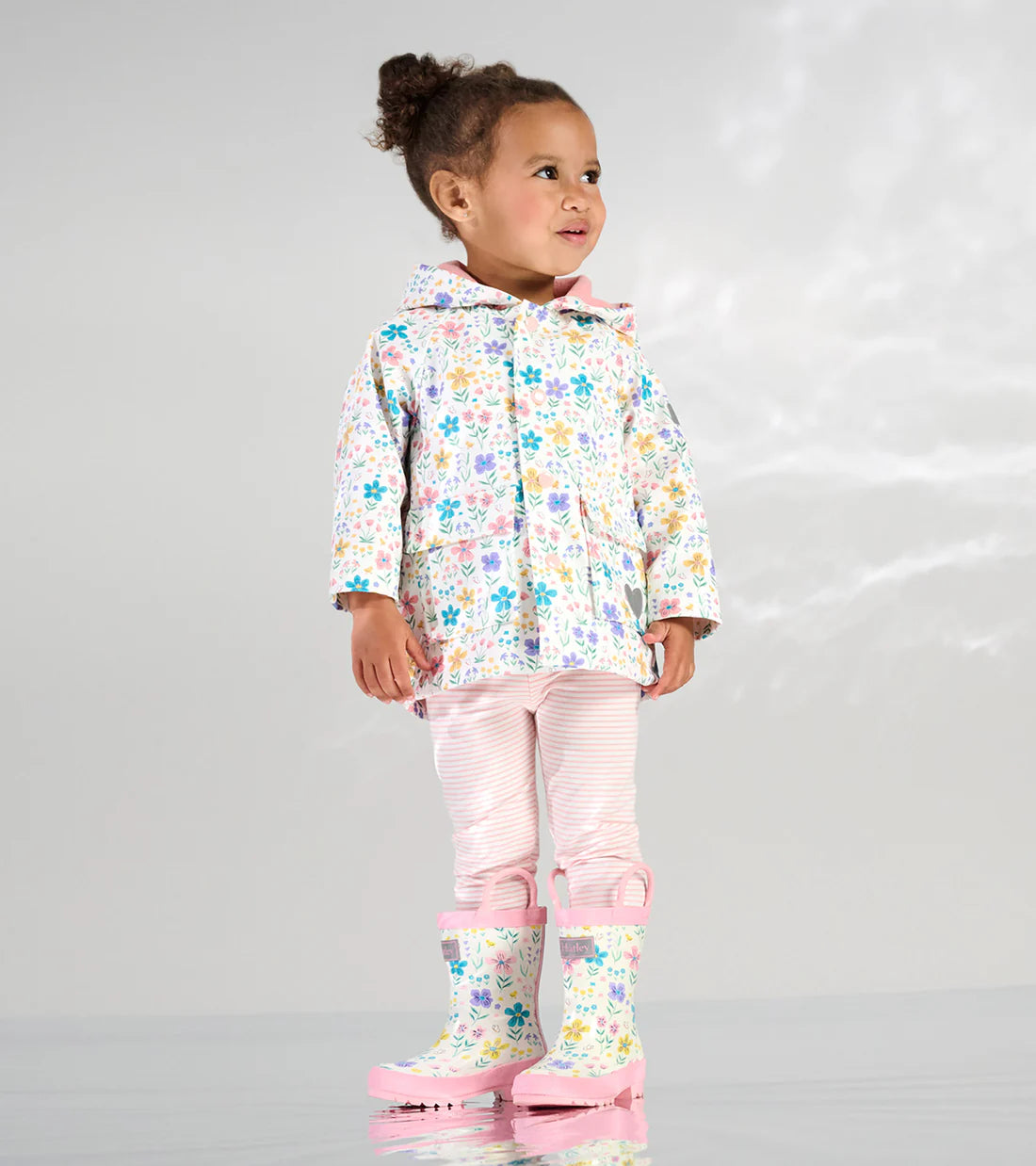 Hatley girls floral raincoat worn with pink leggings and rain boots