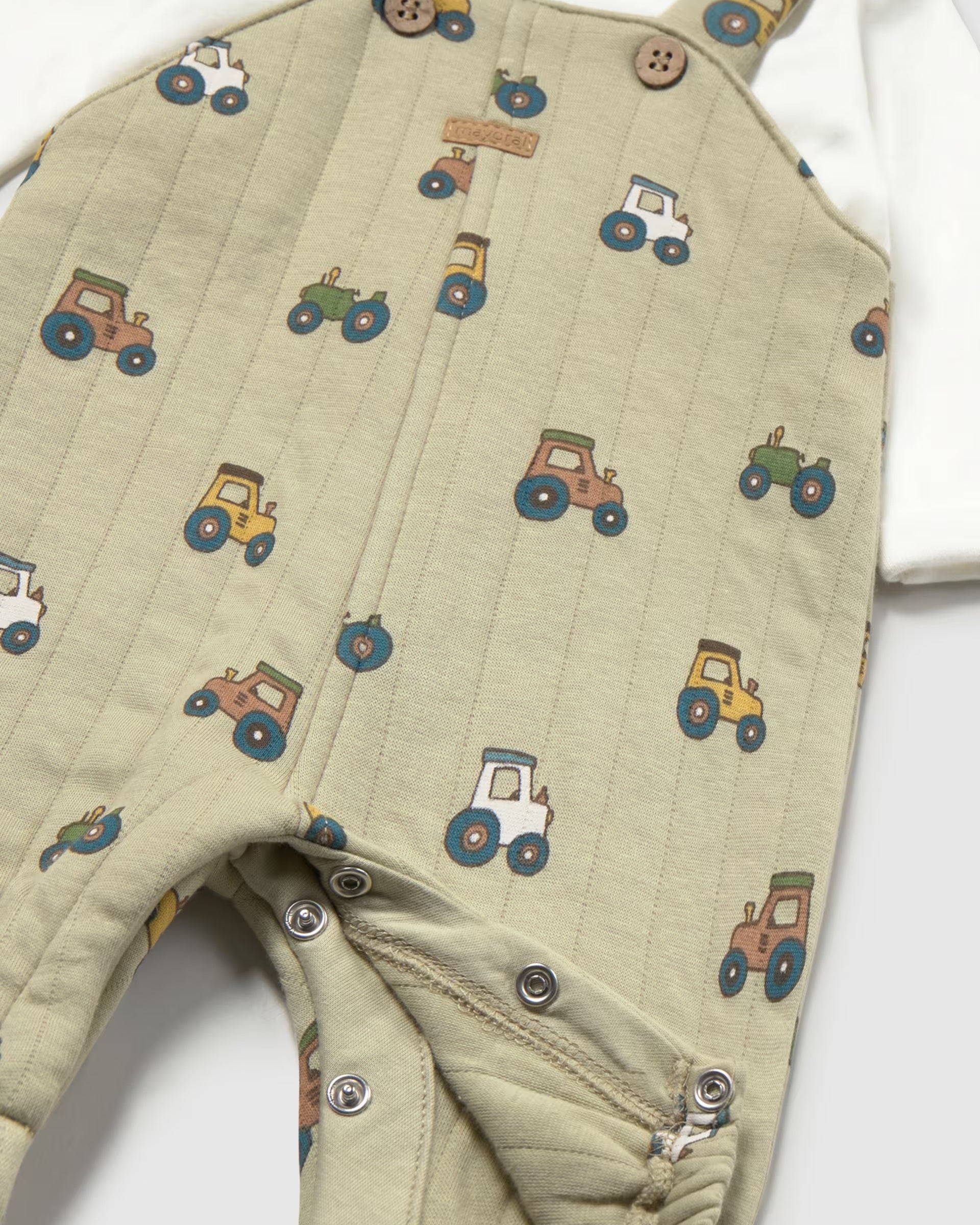 Close-up of colourful tractor print and popper fastening on Mayoral baby dungarees