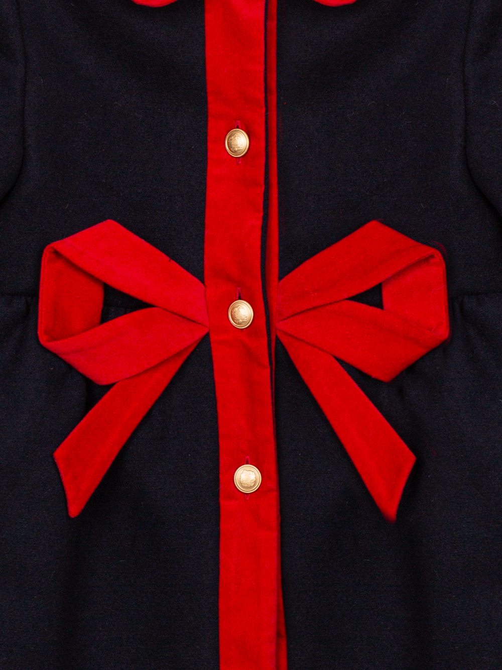 Close-up of Patachou navy coat with red bow trim and gold buttons