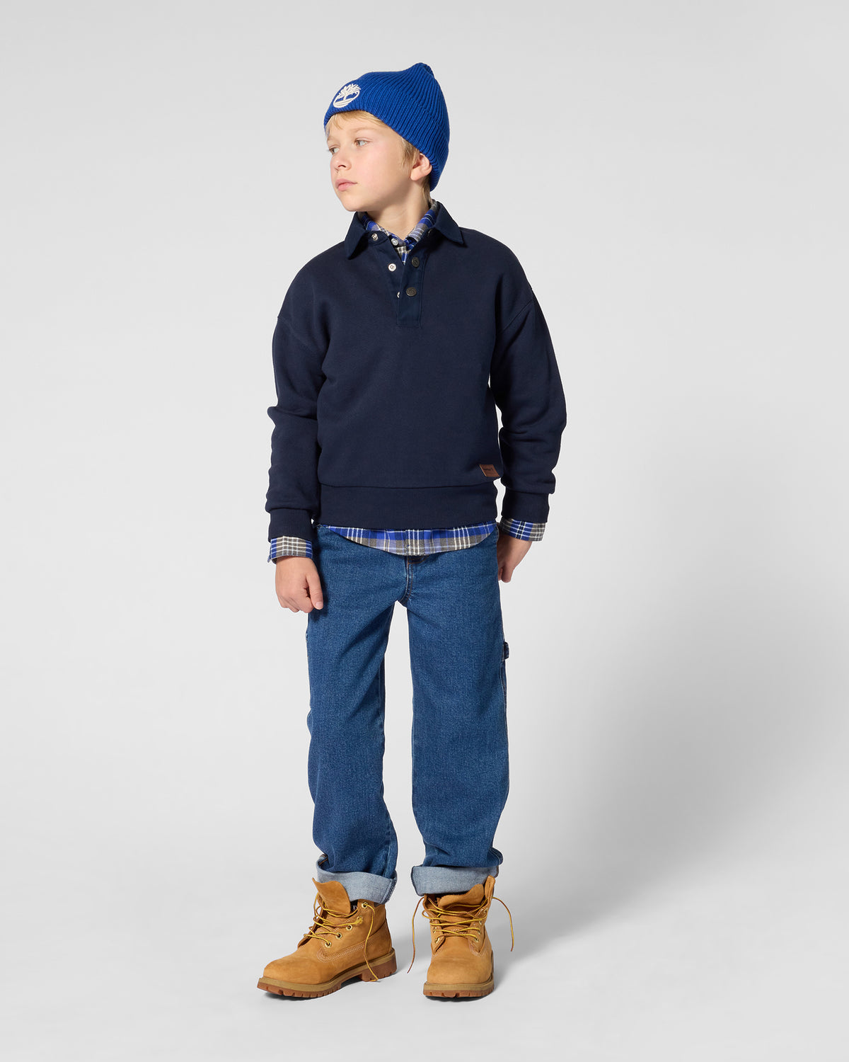 Boy wearing Timberland navy polo collar sweatshirt with blue jeans and tan boots