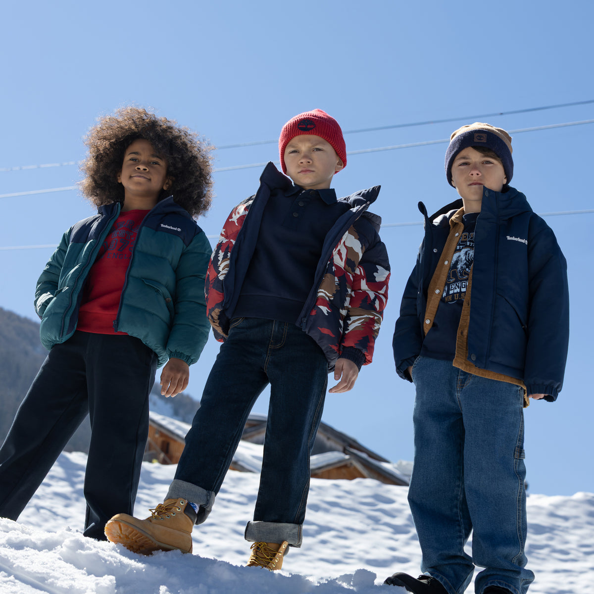 Boys wearing Timberland winter clothing including red graphic sweatshirt and padded jackets