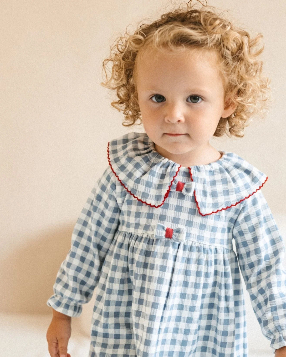 Baby girl wearing Tutto Piccolo indigo gingham dress with ruffle collar
