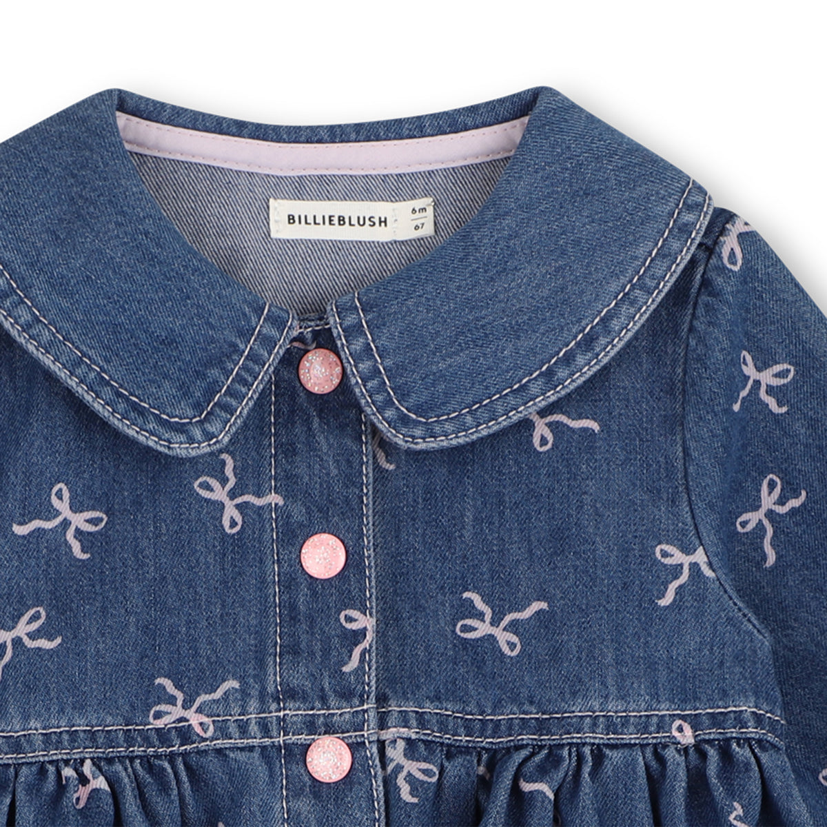 Close-up of Billieblush girls denim dress showing Peter Pan collar, pink buttons and bow print
