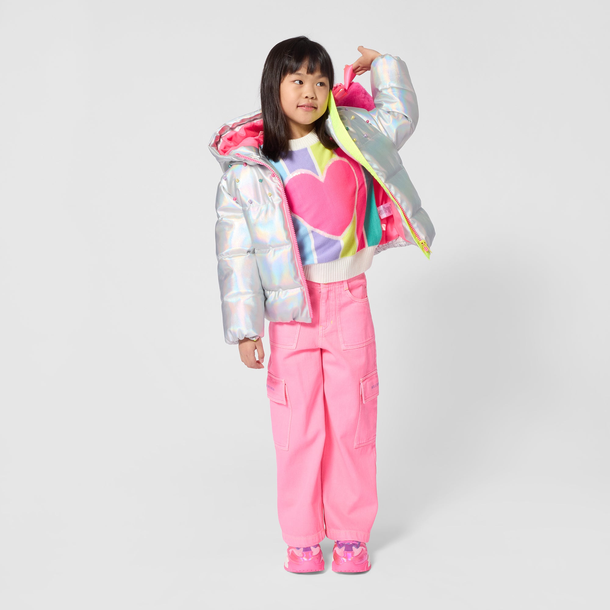 Billieblush girls rainbow stripe heart jumper styled with pink trousers and silver jacket