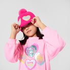 Girl modelling Billieblush pink heart print dress with blue pleated skirt