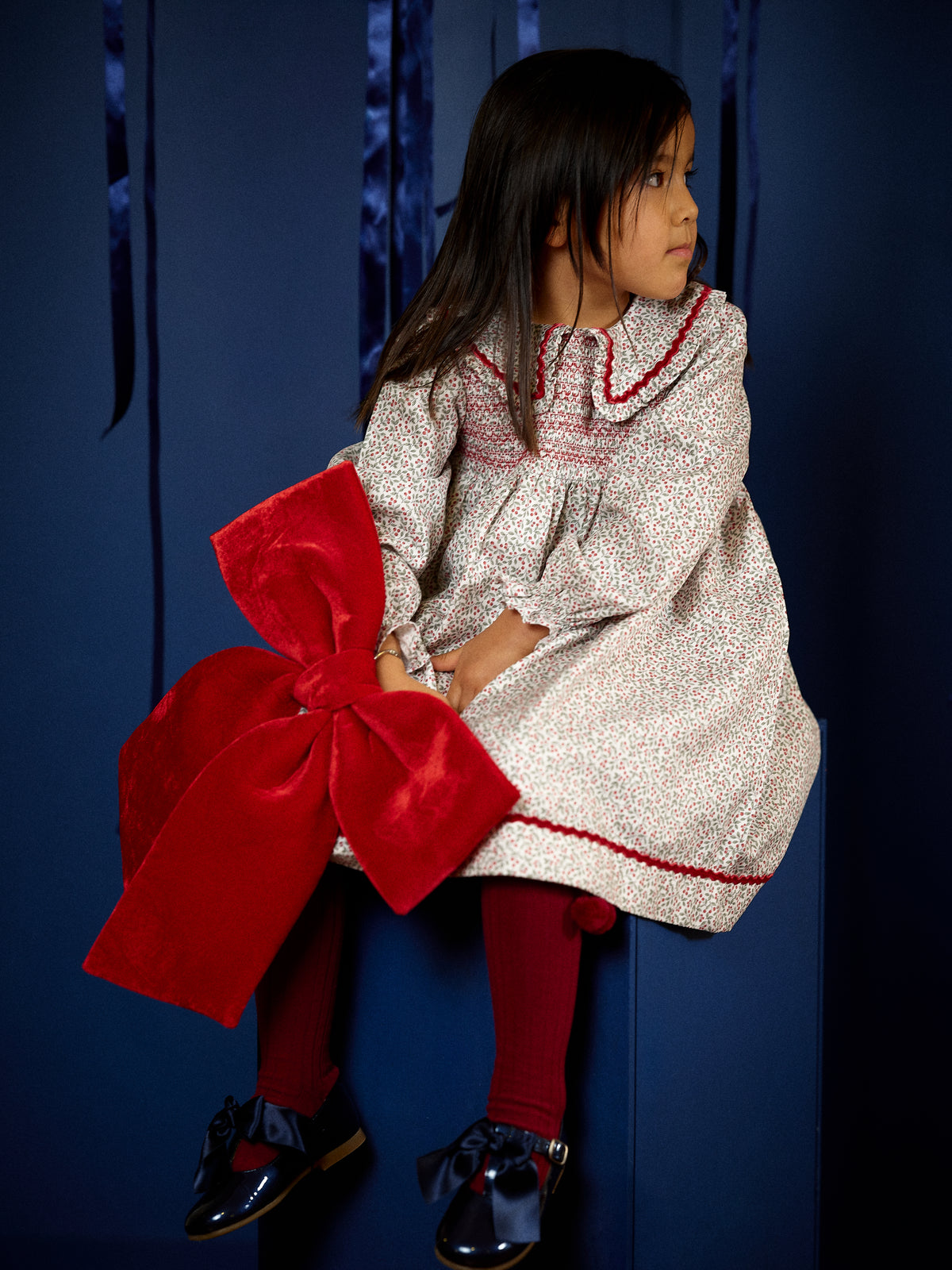 Girl wearing Deolinda Frosty floral smocked Christmas dress with red trim