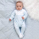 Baby boy wearing Emile et Rose Monty pale blue velour occasion babygrow