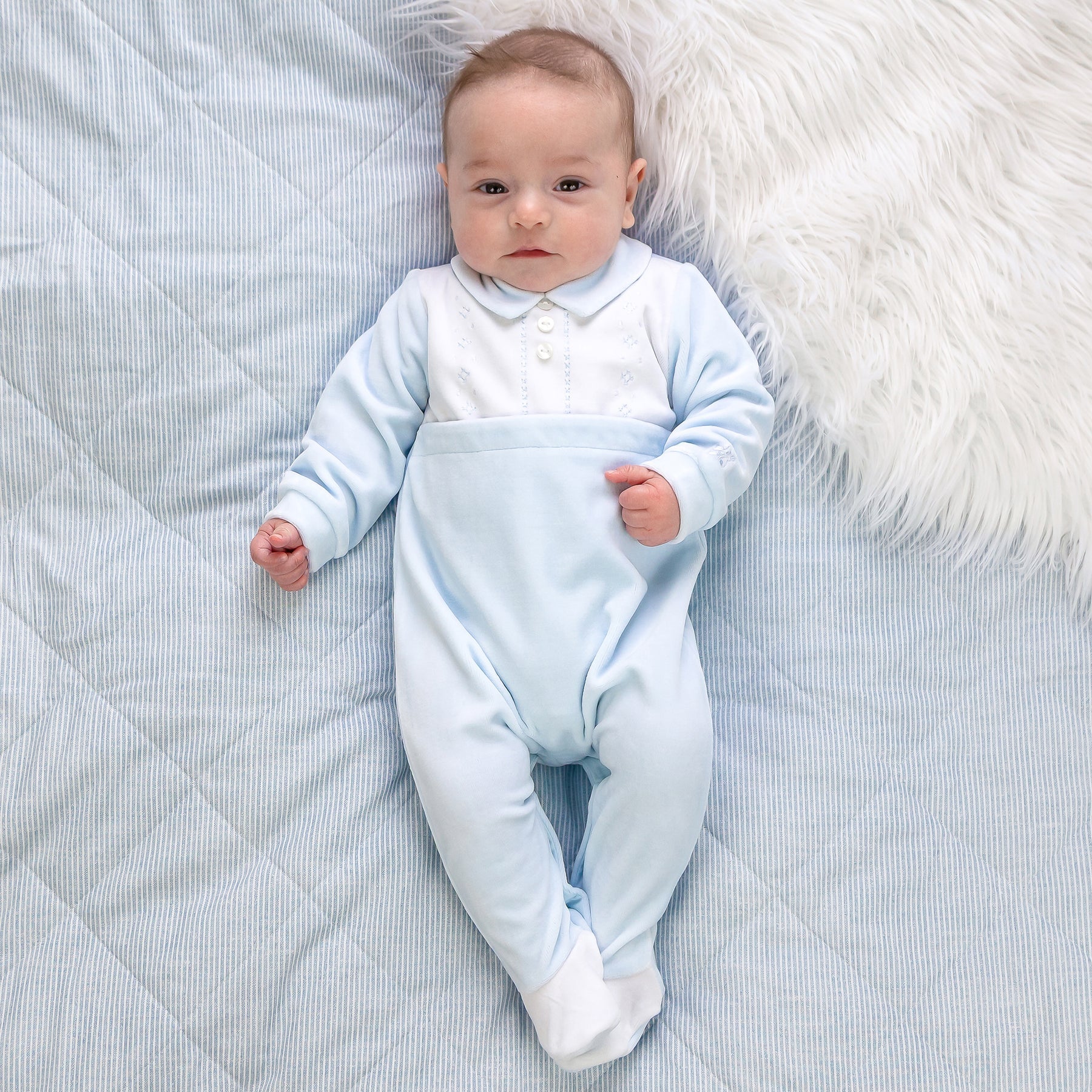 Baby boy wearing Emile et Rose Monty pale blue velour occasion babygrow