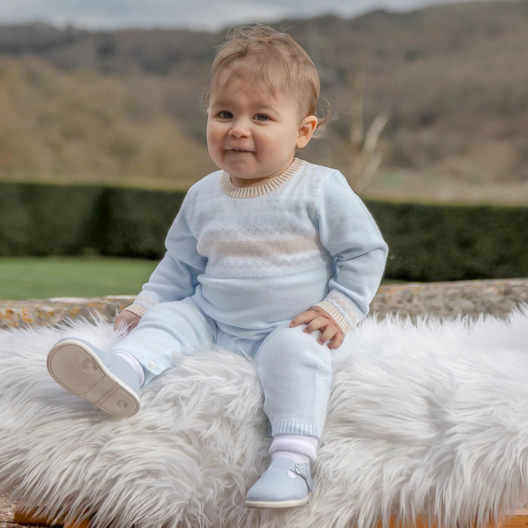 Baby boy wearing Emile et Rose Magnus pale blue knitted babygrow