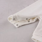 Close-up of the soft ivory velour easy access leg poppers on the Emile et Rose Marshall romper