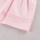 A close-up of a light pink baby girls occasion dress, showing the folded cuff on Emile et Rose dress