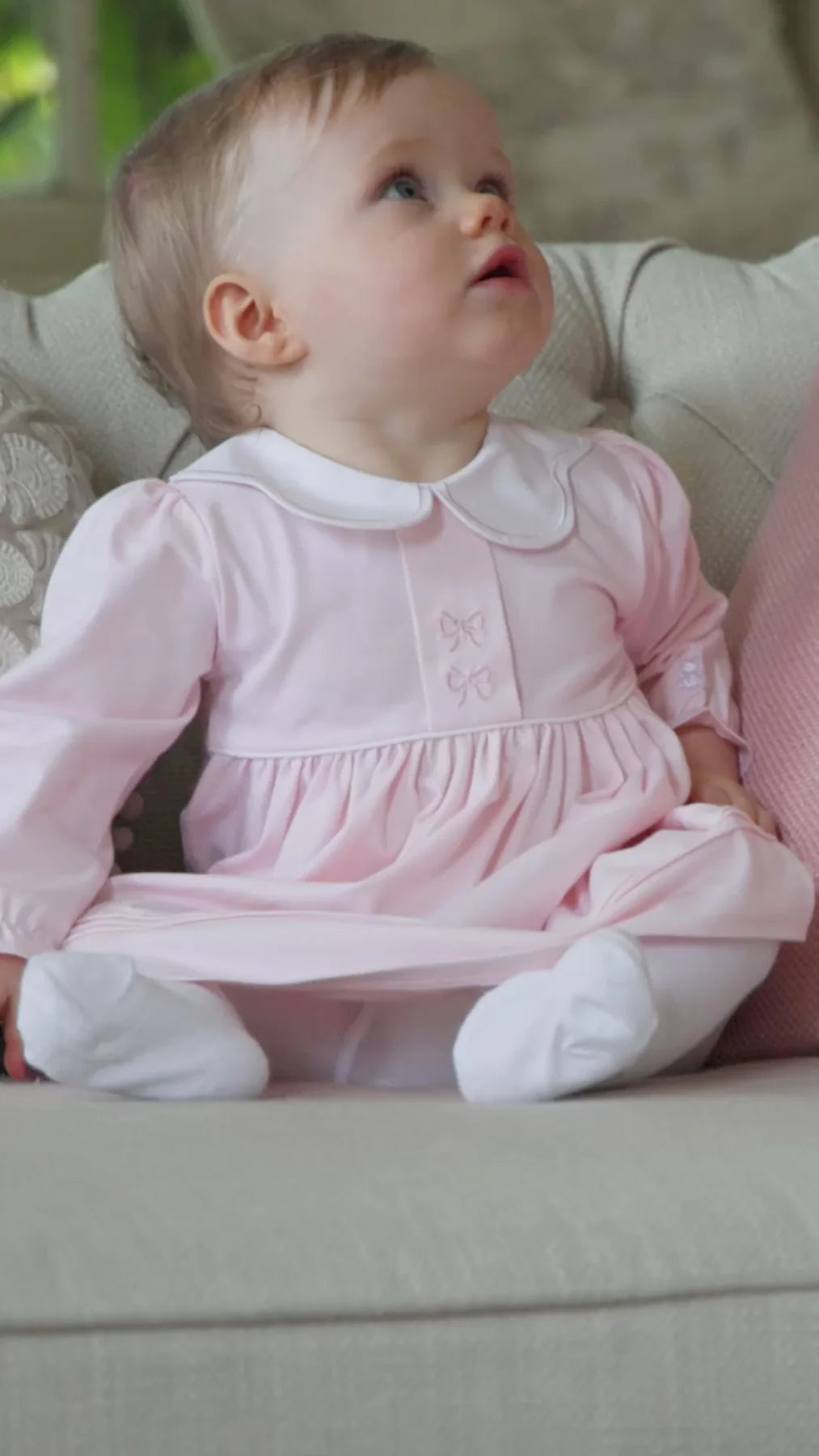 Baby girl wearing the Emile et Rose Maggie pale pink dress and tights