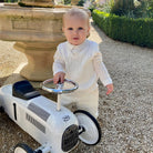 Emile et Rose George ivory christening outfit for baby boys standing by chair