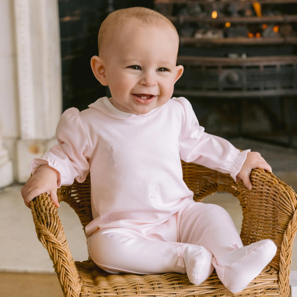 Baby girl smiling in Emile et Rose Kallie Pink Bunny Babygrow sitting on chair