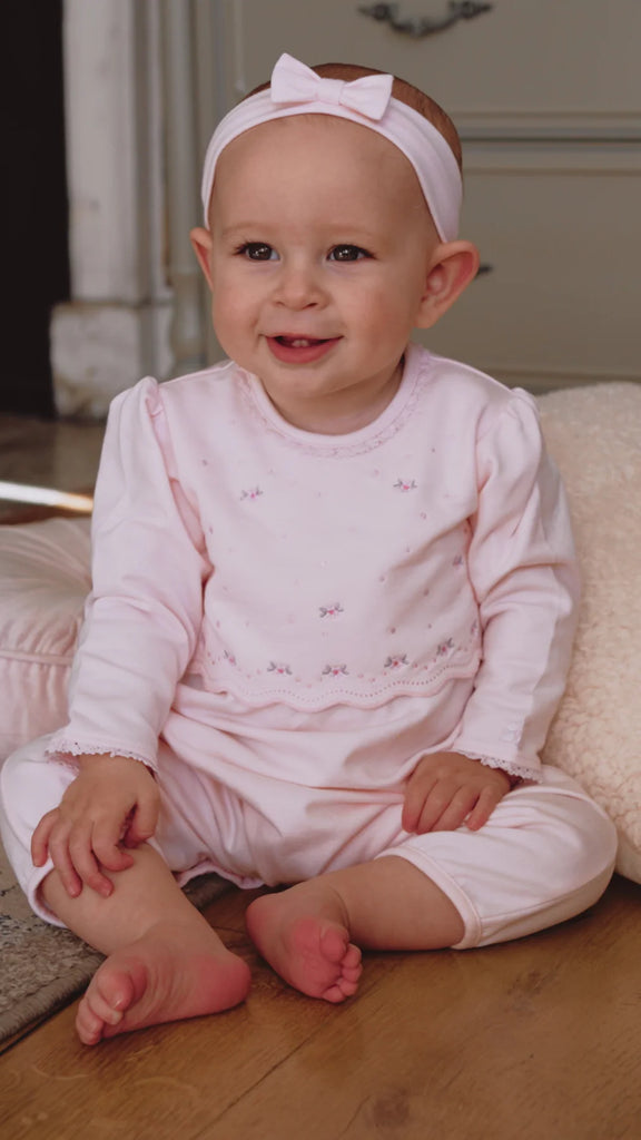 Smiling baby girl wearing Emile et Rose Katerina pink babygrow and headband.
