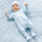 Baby wearing Emile et Rose Kent babygrow with matching hat, full-length view.