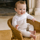 Baby wearing Emile et Rose Kenzie unisex knitted babygrow in stone and white