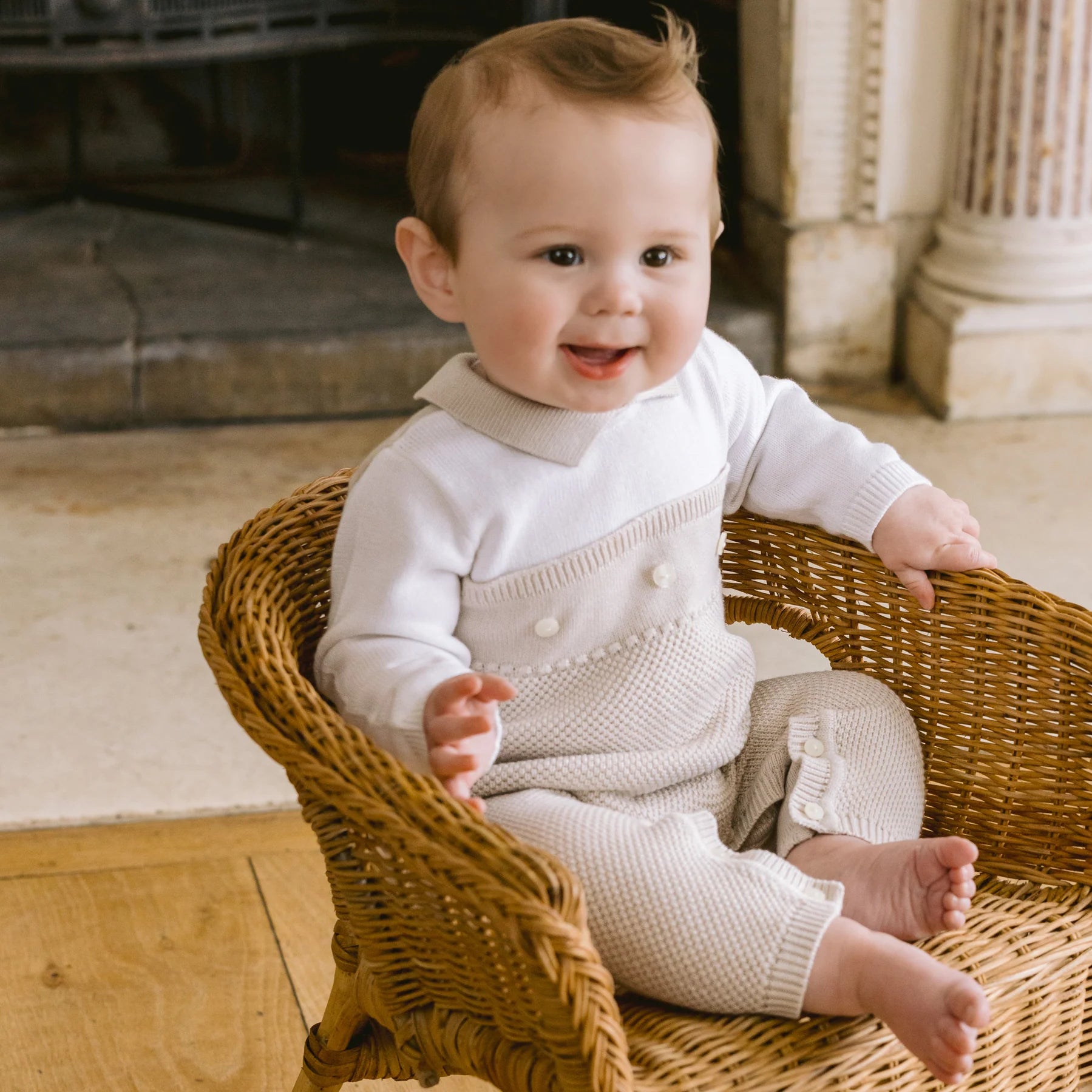 Baby wearing Emile et Rose Kenzie unisex knitted babygrow in stone and white