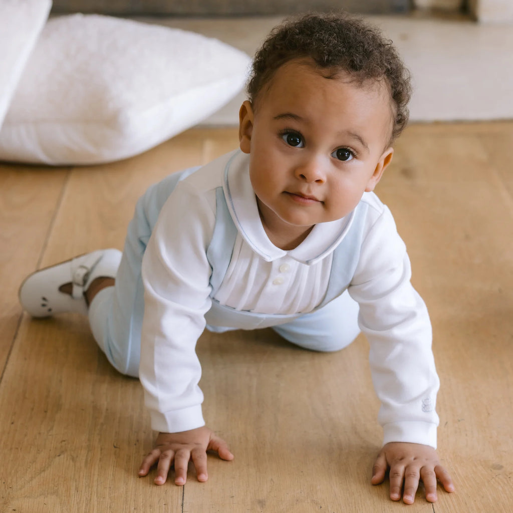 Baby boy crawling on the floor wearing a Emile et Rose white occasion outfit with light blue accents.