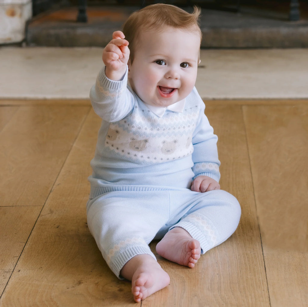 Baby boy raising hand while wearing Emile et Rose Kipling blue teddy knit set.