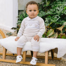 Baby wearing Emile et Rose Kipling knitted outfit with teddy design across chest.