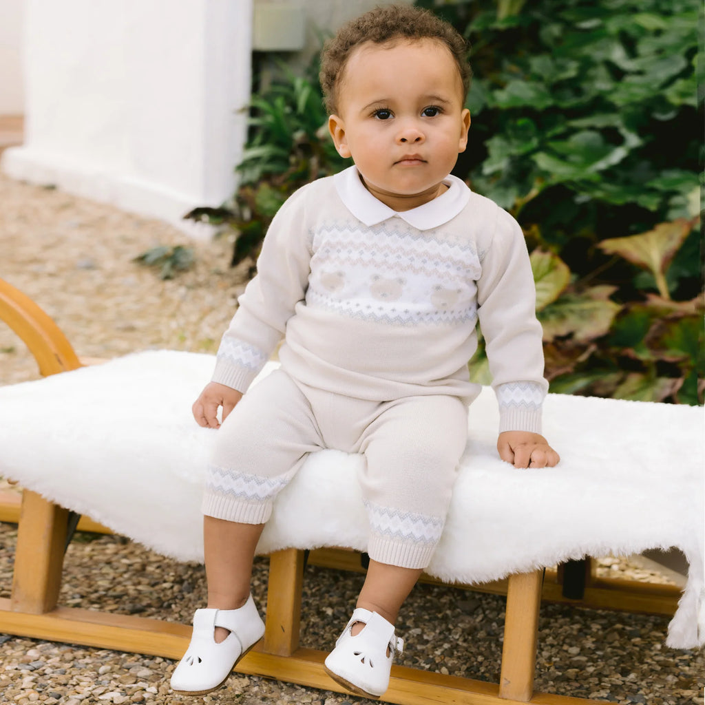 Baby boy in Emile et Rose Kipling fairisle teddy knit outfit, seated outside.