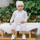 Baby wearing Emile et Rose Kipling unisex knitted teddy outfit and hat.