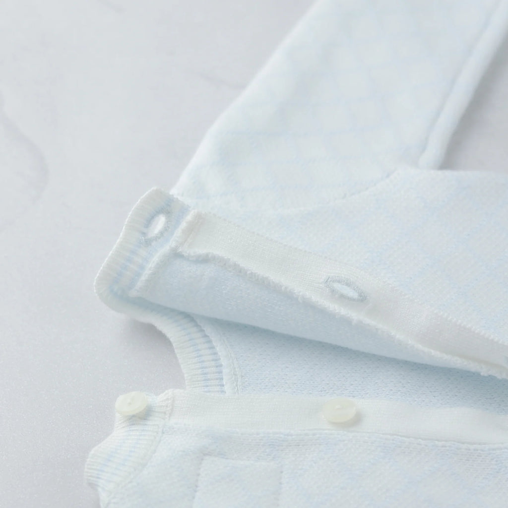 Emile et Rose Light blue baby romper with white buttons on a light gray background