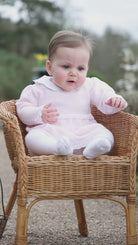 Baby girl wearing the Emile et Rose Millie pale pink knit dress and tights