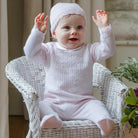  Baby wearing the Emile et Rose Minny pale pink baby girls knit outfit while sitting in a basket