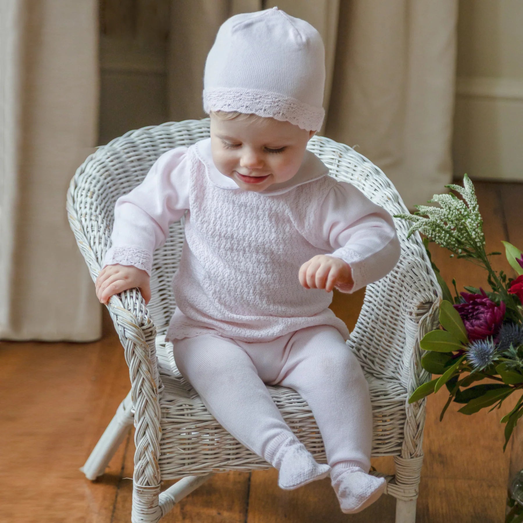 Baby wearing the Emile et Rose Minny pale pink baby girls knit outfit set and matching hat