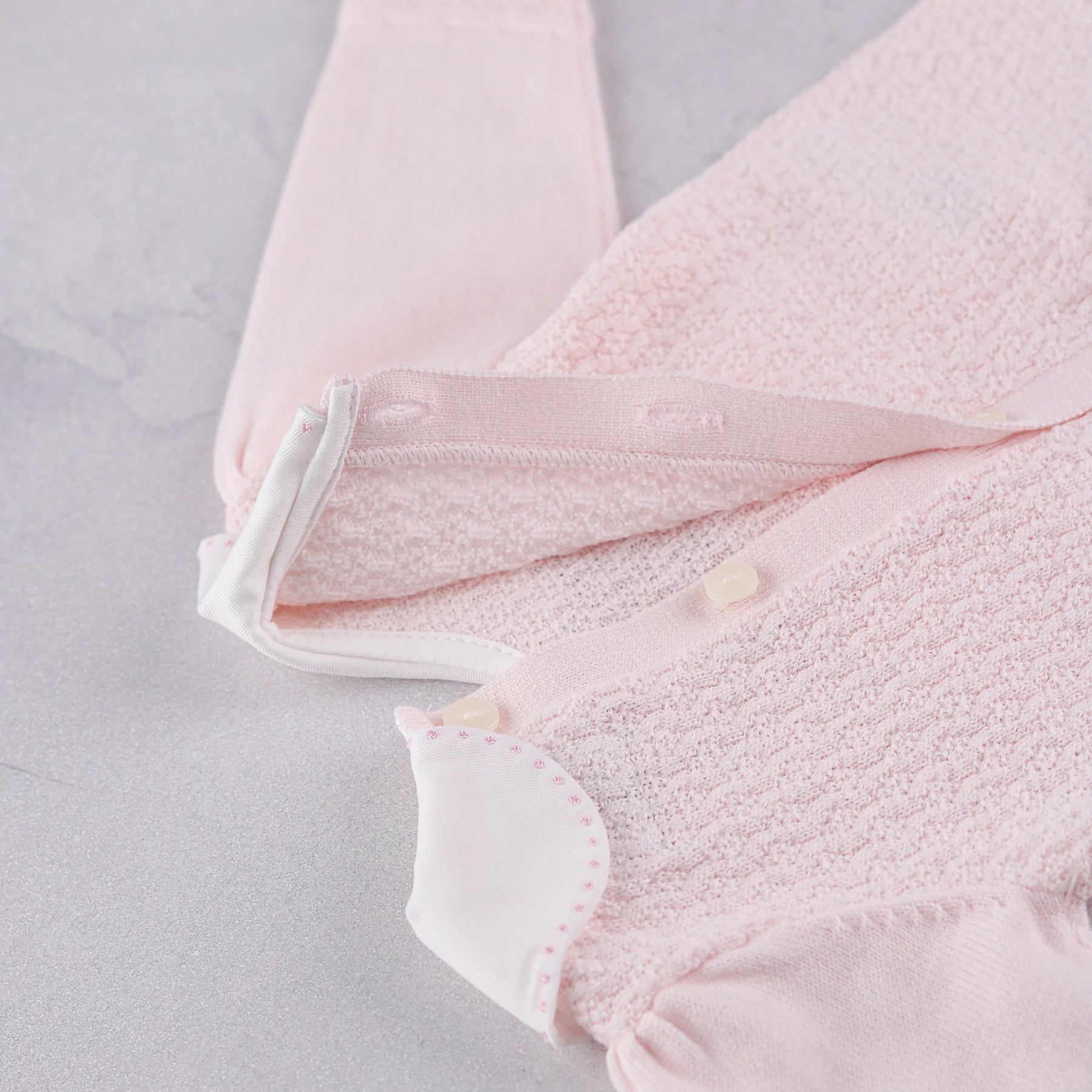 Close-up of the pearlised button fastening on the back of the Emile et Rose Minny knit top