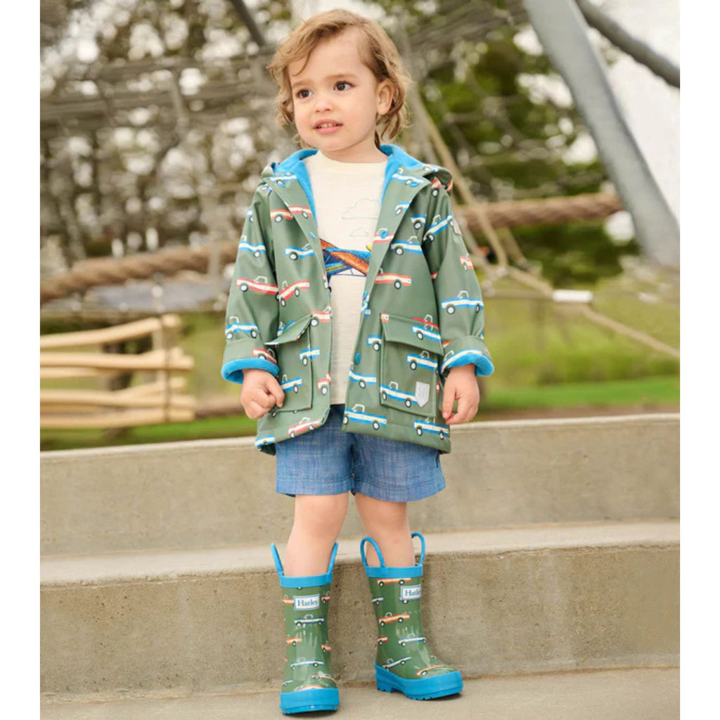 Close-up of green Hatley raincoat for boys featuring blue and red trucks