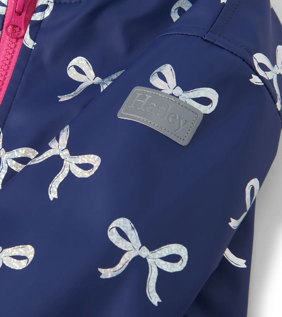 	Hatley zip-up girls rain jacket in navy with foil bows – side angle With brand logo 