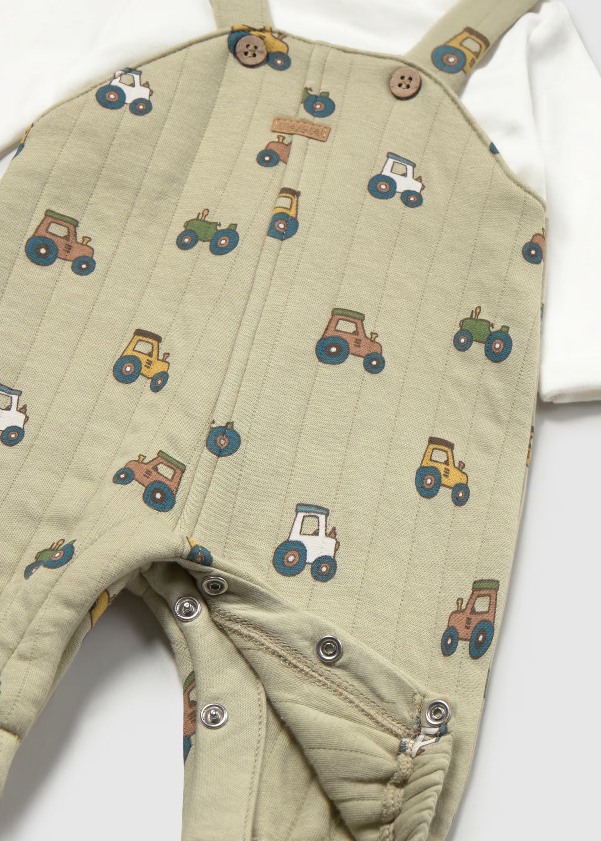    Close-up of colourful tractor print and popper fastening on Mayoral baby dungarees