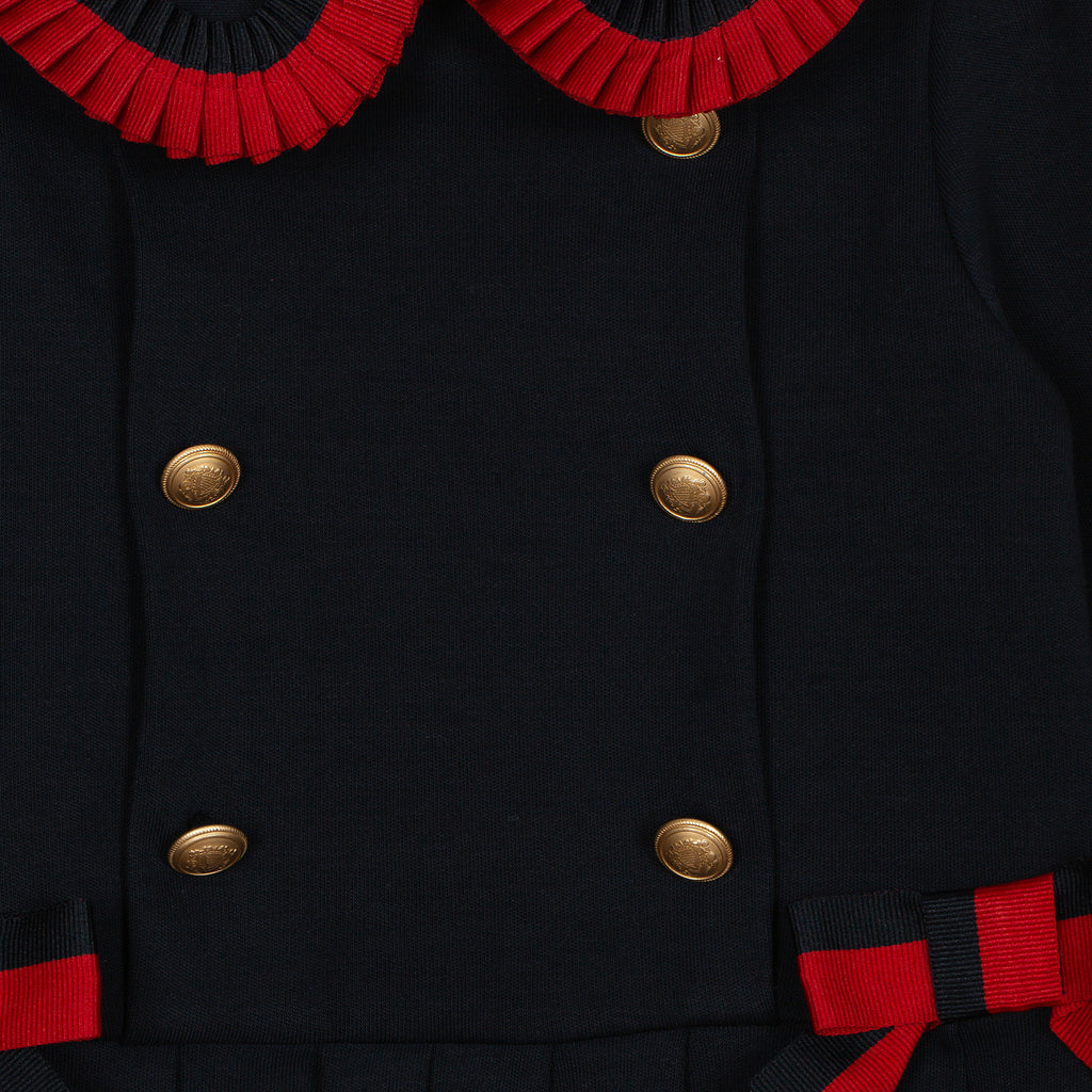 Baby girl wearing Patachou navy and red tartan Christmas dress Close up of designer style buttons 